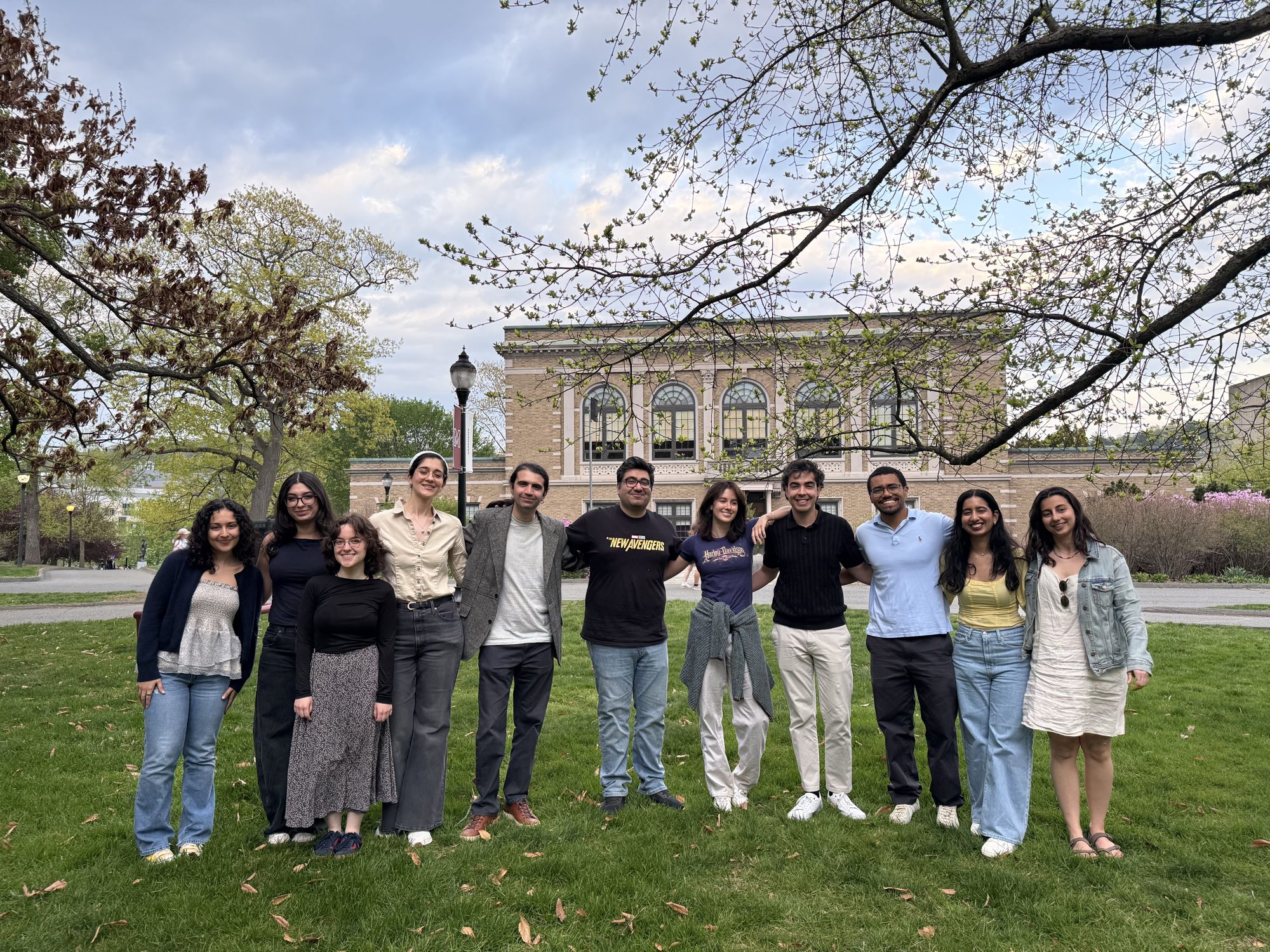 Lab members standing together on a campus lawn under budding trees.